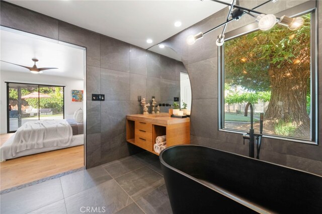 3066 Claret Cir, Atwater, CA 95301 - bathroom with tile walls, ensuite bath, a freestanding bath, vanity, and tile patterned floors