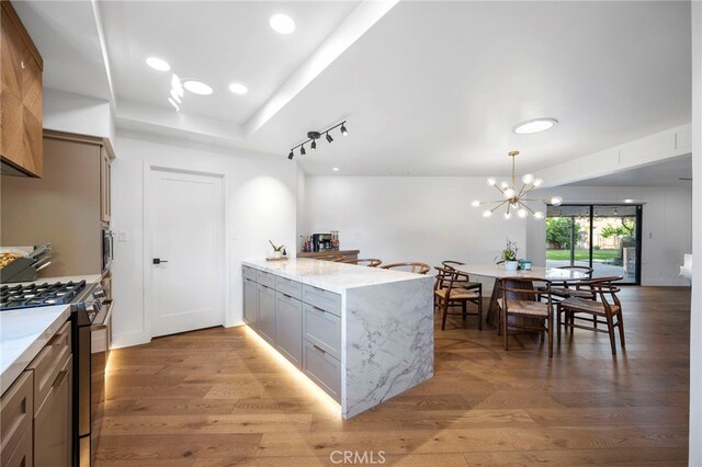 3066 Claret Cir, Atwater, CA 95301 - kitchen featuring a peninsula, gas range, light wood-type flooring, light stone countertops, and a chandelier