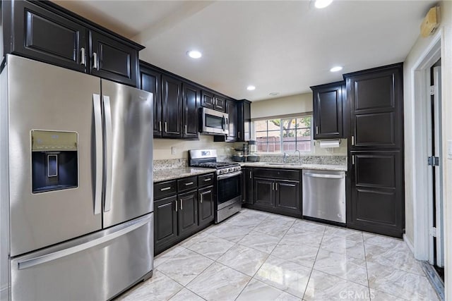 9791 Lee St, Cypress, CA 90630 - kitchen with appliances with stainless steel finishes, dark cabinets, recessed lighting, light stone counters, and light marble finish floors