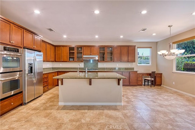 14939 Franklin Ln, Eastvale, CA 92880 - kitchen with stainless steel appliances, under cabinet range hood, brown cabinets, light stone countertops, and recessed lighting