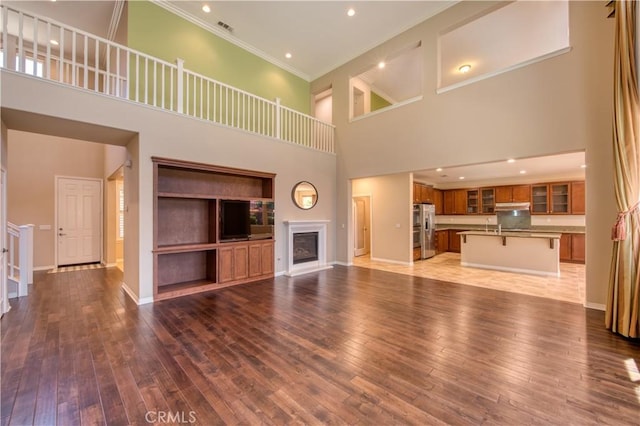 14939 Franklin Ln, Eastvale, CA 92880 - unfurnished living room featuring a towering ceiling, ornamental molding, wood-type flooring, a glass covered fireplace, and recessed lighting