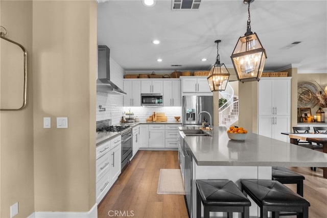 19969 Via Joyce Dr, Saugus, CA 91350 - kitchen with stainless steel appliances, wall chimney range hood, a sink, ornamental molding, and a center island with sink