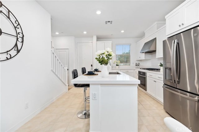 501 Embrook Way, West Covina, CA 91791 - kitchen featuring appliances with stainless steel finishes, wall chimney exhaust hood, an island with sink, a breakfast bar area, and white cabinets