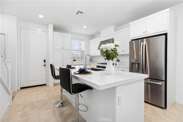 501 Embrook Way, West Covina, CA 91791 - kitchen with stainless steel fridge with ice dispenser, a sink, white cabinets, a breakfast bar area, and light countertops