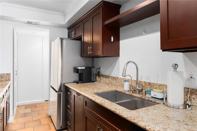 1675 W Lambert Rd Unit G, La Habra, CA 90631 - kitchen featuring a sink, ornamental molding, light stone counters, freestanding refrigerator, and dark brown cabinetry
