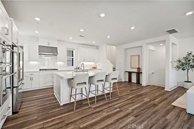 297 Lynx, Irvine, CA 92618 - kitchen with stainless steel appliances, under cabinet range hood, dark wood-type flooring, a center island with sink, and a breakfast bar area