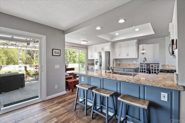 655 Boysenberry Way, Oceanside, CA 92057 - kitchen featuring stainless steel appliances, a peninsula, white cabinetry, a sink, and a tray ceiling