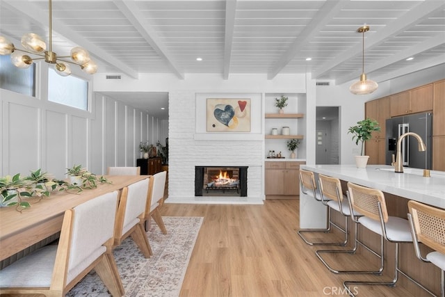 3830 Cedar Ave, Long Beach, CA 90807 - kitchen with beam ceiling, light wood-style floors, high quality fridge, light countertops, and a brick fireplace