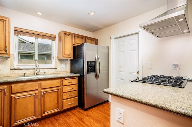 5202 Caliente Dr, Huntington Beach, CA 92649 - kitchen with stainless steel fridge, a sink, wall chimney exhaust hood, light wood-style flooring, and decorative backsplash