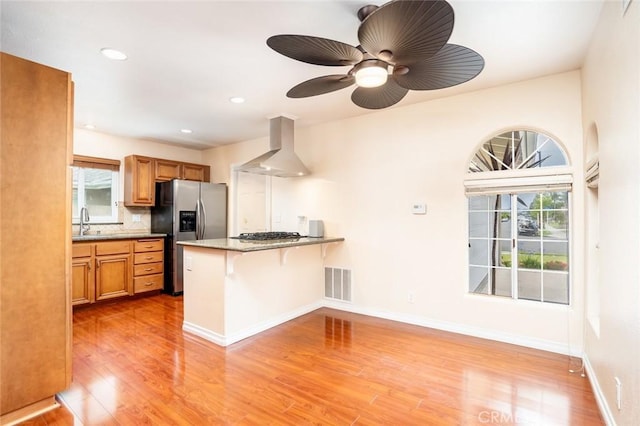 5202 Caliente Dr, Huntington Beach, CA 92649 - kitchen with wall chimney range hood, stainless steel fridge with ice dispenser, a sink, light wood-type flooring, and a peninsula