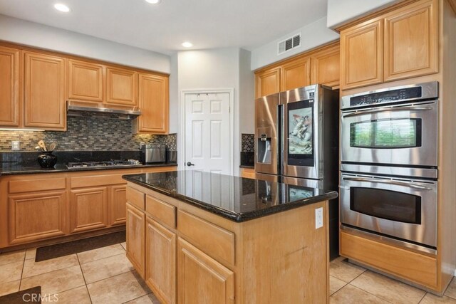 5460 Turin Way, Fontana, CA 92336 - kitchen with stainless steel appliances, under cabinet range hood, a center island, dark stone countertops, and decorative backsplash