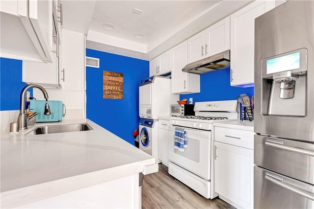 26422 Paseo Carmel Unit 20A, San Juan Capistrano, CA 92675 - kitchen featuring under cabinet range hood, gas range gas stove, stainless steel fridge with ice dispenser, stacked washer and clothes dryer, and a sink