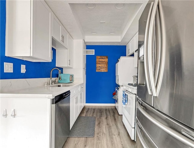 26422 Paseo Carmel Unit 20A, San Juan Capistrano, CA 92675 - kitchen with stainless steel appliances, a sink, a tray ceiling, light wood finished floors, and white cabinets
