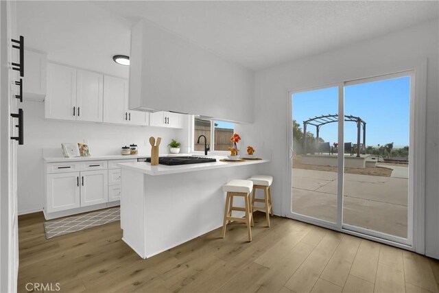 24855 Sundial Way, Moreno Valley, CA 92557 - kitchen featuring light wood-type flooring, white cabinetry, a peninsula, and light countertops