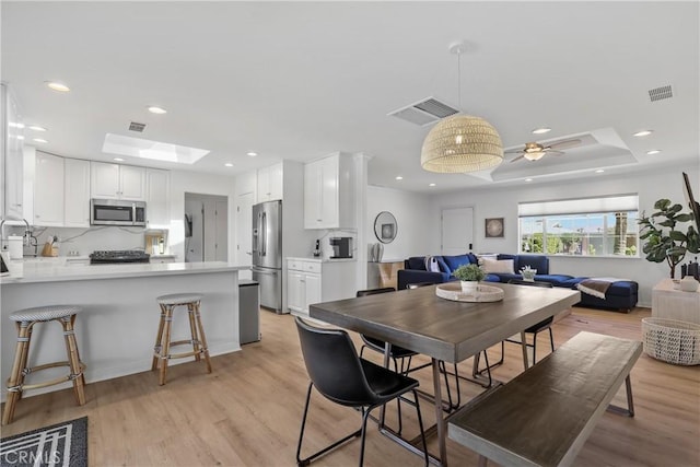 77355 Minnesota Ave, Palm Desert, CA 92211 - dining space with light wood-style floors, recessed lighting, a tray ceiling, a skylight, and a ceiling fan