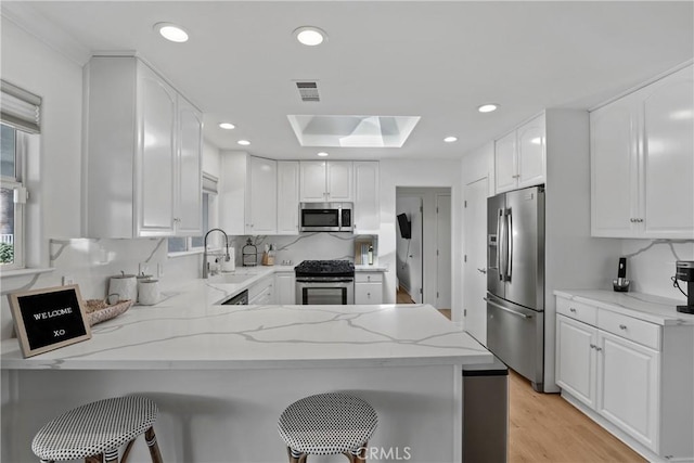 77355 Minnesota Ave, Palm Desert, CA 92211 - kitchen featuring appliances with stainless steel finishes, a sink, a skylight, a peninsula, and light stone counters