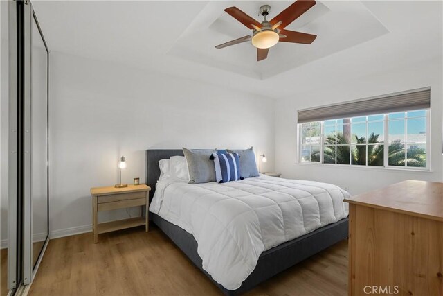 77355 Minnesota Ave, Palm Desert, CA 92211 - bedroom with a raised ceiling, light wood-style floors, and a ceiling fan