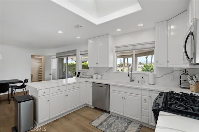 77355 Minnesota Ave, Palm Desert, CA 92211 - kitchen with appliances with stainless steel finishes, a sink, a peninsula, light wood-style flooring, and plenty of natural light