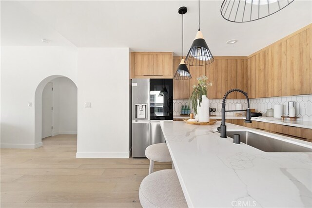 3927 Welland Ave, Los Angeles, CA 90008 - kitchen with stainless steel refrigerator with ice dispenser, a sink, tasteful backsplash, arched walkways, and modern cabinets