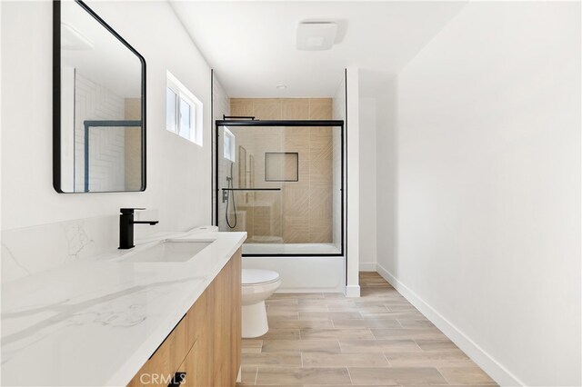 3927 Welland Ave, Los Angeles, CA 90008 - full bath featuring vanity, toilet, shower / bath combination with glass door, wood finished floors, and baseboards