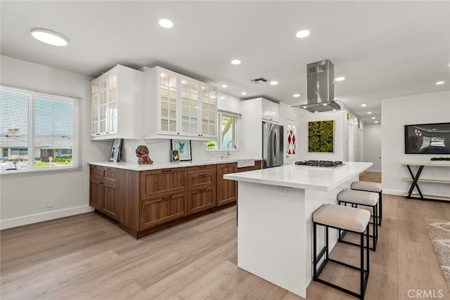 2116 E Thackery St, West Covina, CA 91791 - kitchen featuring island exhaust hood, appliances with stainless steel finishes, brown cabinets, a kitchen breakfast bar, and baseboards