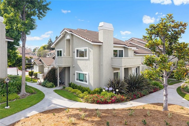 549 Springbrook N, Irvine, CA 92614 - view of home's exterior with a chimney, stucco siding, a tile roof, and a balcony