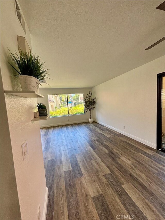 113 Pearl Unit 106, Laguna Niguel, CA 92677 - unfurnished living room with dark wood-style flooring, a textured ceiling, baseboards, and a ceiling fan