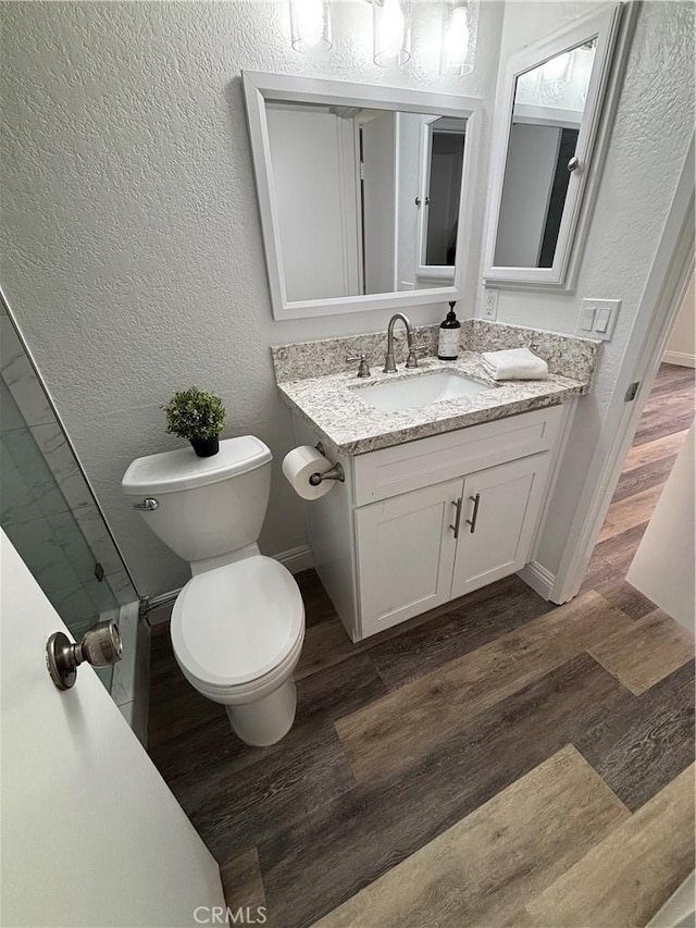 113 Pearl Unit 106, Laguna Niguel, CA 92677 - bathroom with wood finished floors, vanity, toilet, baseboards, and a textured wall
