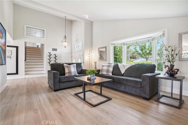 25585 Chrisanta Dr, Mission Viejo, CA 92691 - living area featuring high vaulted ceiling, stairway, light wood-style floors, and baseboards