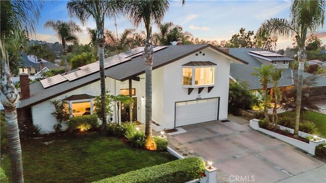 25585 Chrisanta Dr, Mission Viejo, CA 92691 - view of front of house with stucco siding, driveway, an attached garage, roof mounted solar panels, and a chimney
