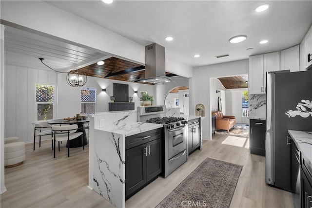 4470 Colbath Ave, Sherman Oaks, CA 91423 - kitchen featuring appliances with stainless steel finishes, island range hood, light stone counters, light wood-type flooring, and dark cabinetry
