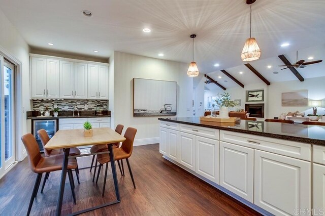 1530 Stewart St, Oceanside, CA 92054 - kitchen featuring dark wood finished floors, decorative light fixtures, wine cooler, white cabinets, and backsplash