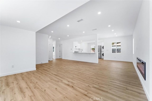 2731 Armour Ln, Redondo Beach, CA 90278 - unfurnished living room featuring light wood finished floors, stacked washer and clothes dryer, recessed lighting, heating unit, and a glass covered fireplace