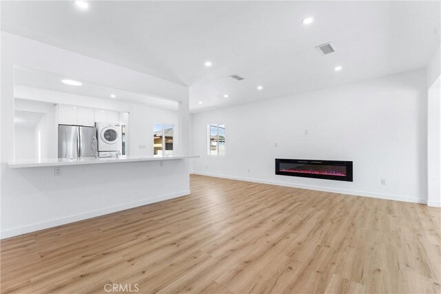 2731 Armour Ln, Redondo Beach, CA 90278 - unfurnished living room with stacked washer / drying machine, light wood-style floors, recessed lighting, and a glass covered fireplace