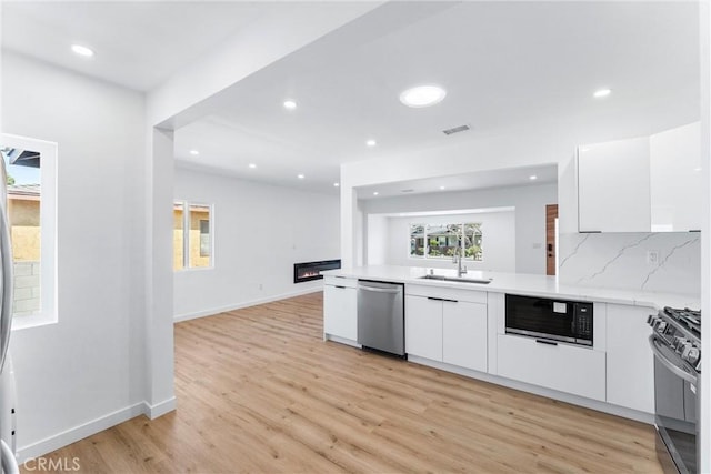 2731 Armour Ln, Redondo Beach, CA 90278 - kitchen with appliances with stainless steel finishes, white cabinetry, modern cabinets, light countertops, and light wood-type flooring