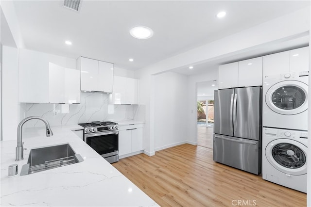 2731 Armour Ln, Redondo Beach, CA 90278 - kitchen with stainless steel appliances, stacked washer / dryer, modern cabinets, white cabinetry, and light stone counters