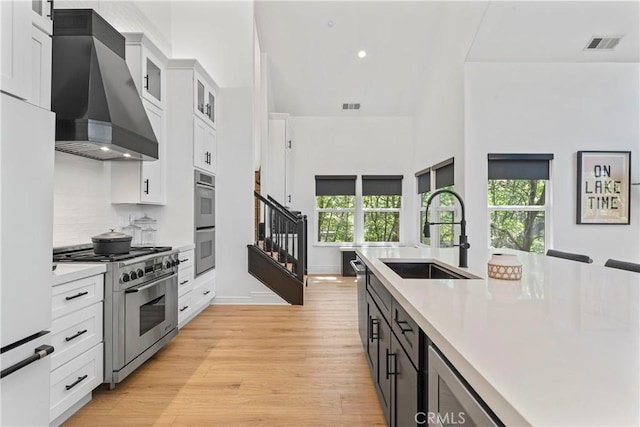 1019 Pintail Cir, Lake Arrowhead, CA 92352 - kitchen featuring wall chimney exhaust hood, appliances with stainless steel finishes, light countertops, white cabinetry, and light wood-style floors
