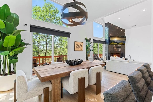 1019 Pintail Cir, Lake Arrowhead, CA 92352 - dining room featuring wood finished floors, a towering ceiling, a premium fireplace, and recessed lighting