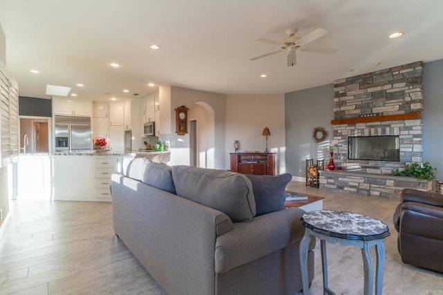 30646 Red Hawk Rd, Valley Center, CA 92082 - living room with ceiling fan, arched walkways, a stone fireplace, recessed lighting, and light wood-style flooring