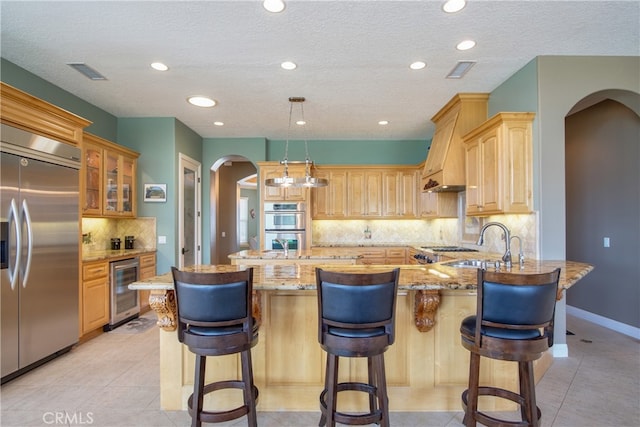 41380 La Sierra Rd, Temecula, CA 92591 - kitchen with appliances with stainless steel finishes, arched walkways, wine cooler, a peninsula, and light stone countertops