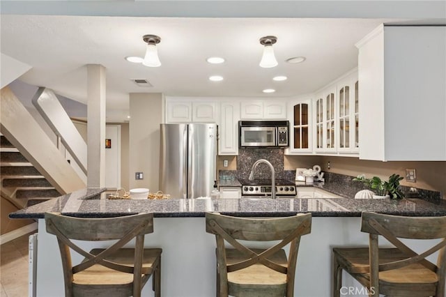 2787 Pine Creek Cir, Fullerton, CA 92835 - kitchen with stainless steel appliances, glass insert cabinets, a peninsula, a breakfast bar, and white cabinets