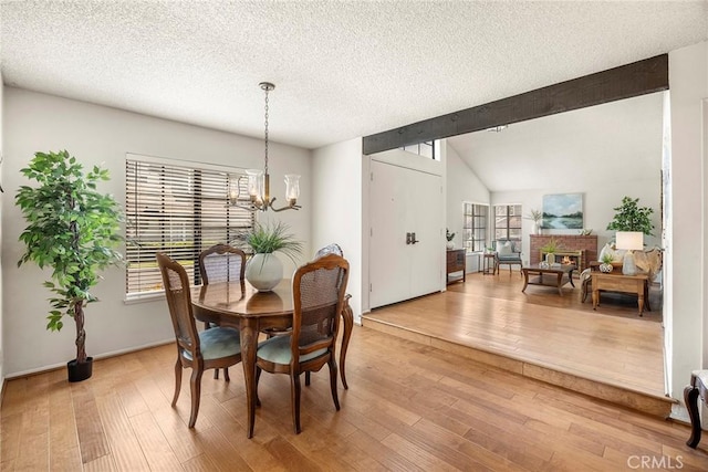 77 S Havenwood Unit 27, Irvine, CA 92614 - dining space featuring a chandelier, light wood finished floors, a textured ceiling, and a fireplace
