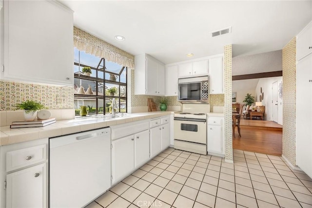 77 S Havenwood Unit 27, Irvine, CA 92614 - kitchen featuring white appliances, tile countertops, white cabinetry, tasteful backsplash, and recessed lighting