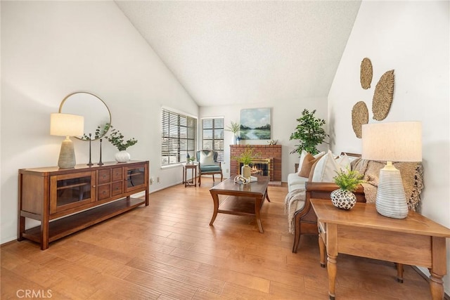 77 S Havenwood Unit 27, Irvine, CA 92614 - sitting room featuring a fireplace, light wood-type flooring, high vaulted ceiling, and a textured ceiling