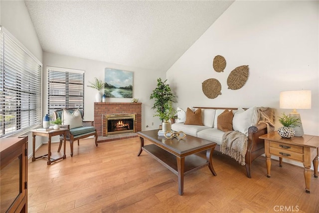 77 S Havenwood Unit 27, Irvine, CA 92614 - living area with vaulted ceiling, a textured ceiling, a fireplace, and light wood-style flooring