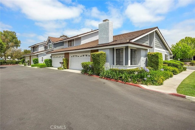 77 S Havenwood Unit 27, Irvine, CA 92614 - view of side of home featuring a chimney, stucco siding, a garage, and asphalt driveway