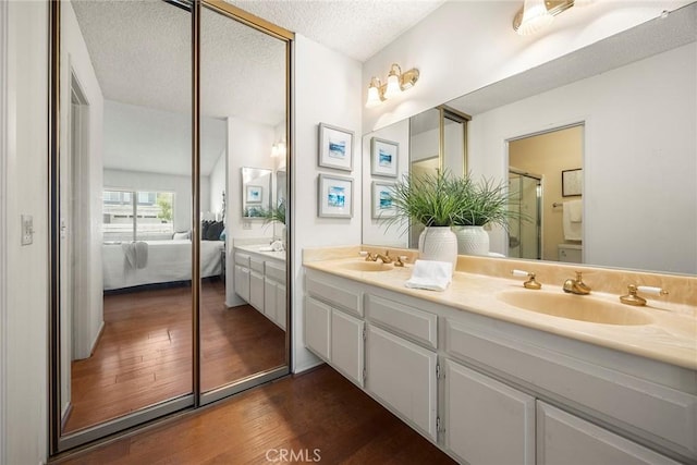 77 S Havenwood Unit 27, Irvine, CA 92614 - bathroom featuring ensuite bath, wood finished floors, double vanity, and a textured ceiling