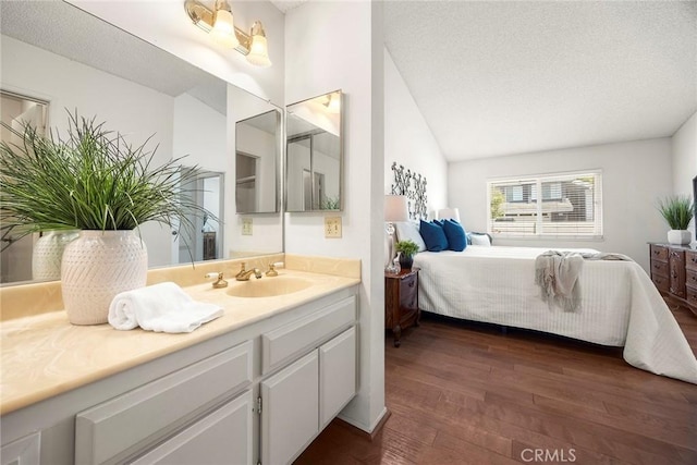 77 S Havenwood Unit 27, Irvine, CA 92614 - ensuite bathroom with hardwood / wood-style floors, vanity, vaulted ceiling, and a textured ceiling