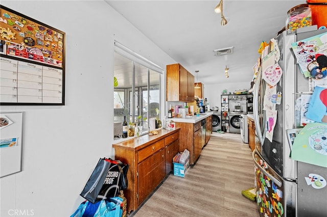 18251 Hiawatha Rd, Apple Valley, CA 92307 - kitchen with washing machine and clothes dryer, brown cabinets, light wood finished floors, light countertops, and freestanding refrigerator