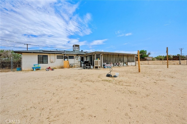 18251 Hiawatha Rd, Apple Valley, CA 92307 - rear view of house with a sunroom, solar panels, and stucco siding